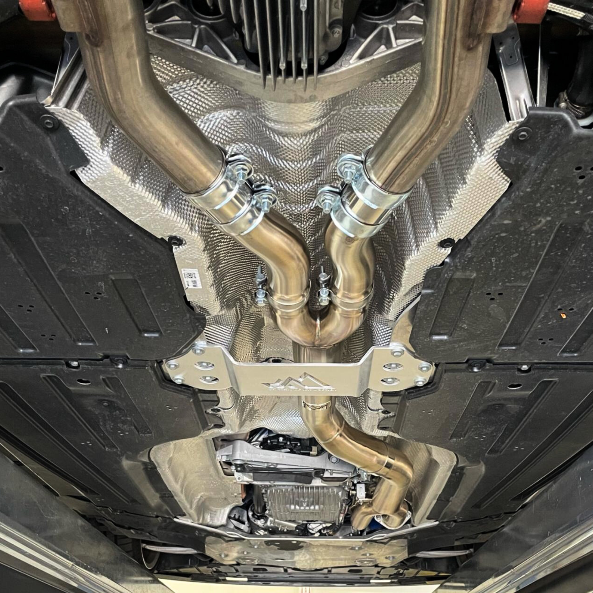 Complete BMW performance exhaust system with downpipes and heat shields installed - full exhaust installation service at Bimmer Tech in Los Angeles and Orange County