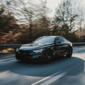Black BMW M4 driving on scenic highway - BMW Road-Trip Ready Check ensures your vehicle is prepared for long-distance travel at Bimmer Tech